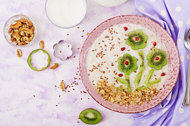 Mingau de aveia saboroso e saudável com kiwi, romã e nozes. Café da manhã saudável. Comida de fitness. Nutrição apropriada. Vista do topo
