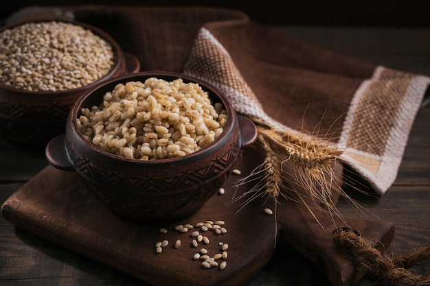 Mingau de cereal de cevada saborosa em uma tigela sobre fundo escuro de madeira Conceito de comida saudável e dietética