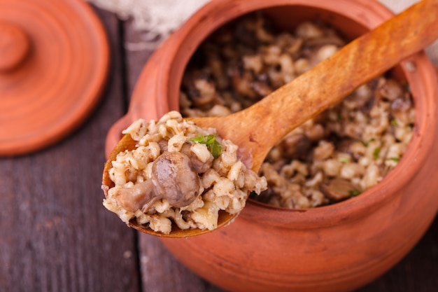 Mingau de cevada com cogumelos em uma panela de barro