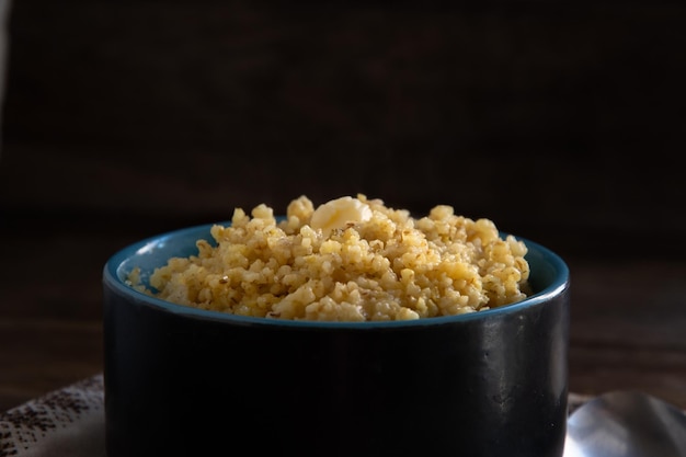 Mingau de trigo em uma tigela de cerâmica e uma colher em uma mesa de madeira Comida caseira