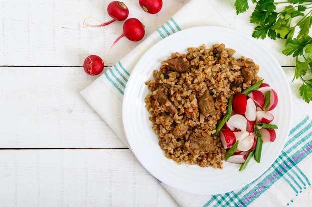 Mingau de trigo sarraceno com pedaços de carne e uma salada de rabanetes