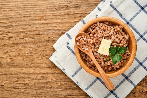 Mingau de trigo sarraceno em uma tigela com folhas de salsa e manteiga