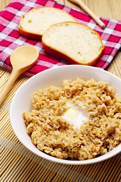 Mingau em uma tigela com manteiga em uma mesa de madeira