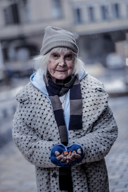 Minha comida. pobre mulher sorrindo para você enquanto segura um punhado de doces