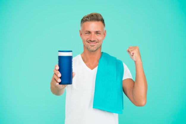 Minha escolha masculina de beleza e saúde rotina matinal diária homem sem barba tem cabelo elegante ou corte de cabelo pronto para tomar banho com toalha homem bonito com xampu cara forte apresentando garrafa de gel