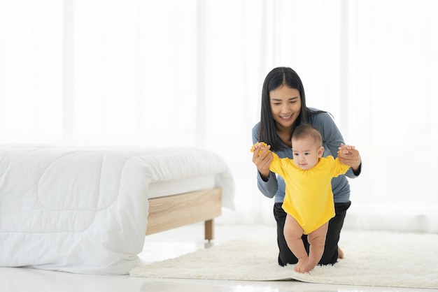 Minha garotinha dá os primeiros passos. família bebê feliz aprendendo a andar com a ajuda da mãe em casa