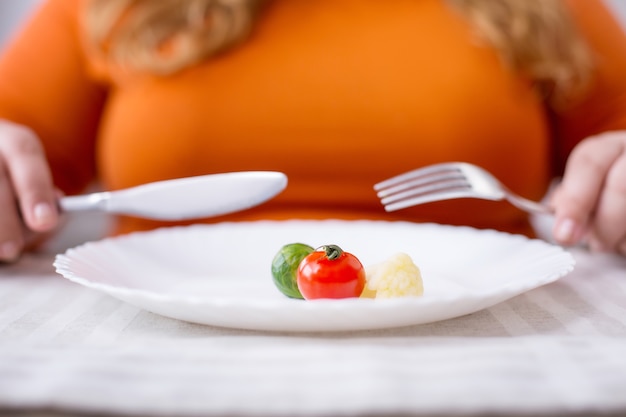 Minha nova vida. jovem mulher com excesso de peso sentada à mesa comendo alimentos saudáveis