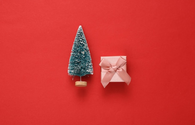 Mini árbol de Navidad con caja de regalo sobre fondo rojo Año nuevo o fondo de Navidad Vista superior Endecha plana