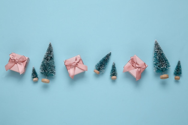 Mini árvores de Natal com caixas de presentes em fundo azul Ano novo ou fundo de natal Vista superior Postura plana