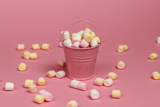 Mini balde com muitos marshmallows em um fundo rosa pastel. minimalismo. doces