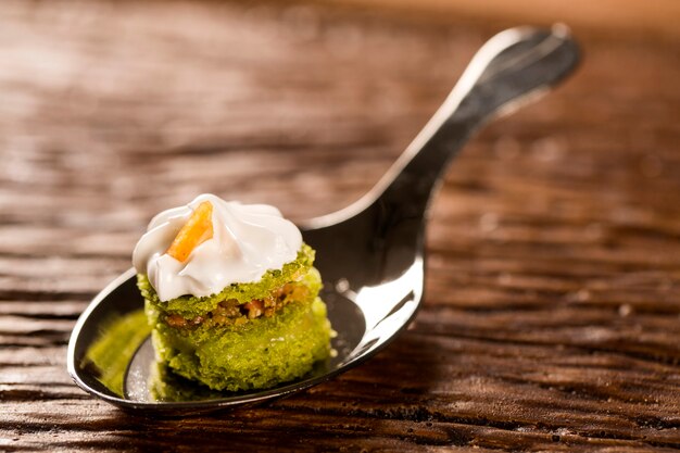 Mini bizcocho desnudo de jugo de limón relleno de gelatina de cupuaçu, praliné de nueces y merengue suizo en una cuchara. Prueba la gastronomía para picar