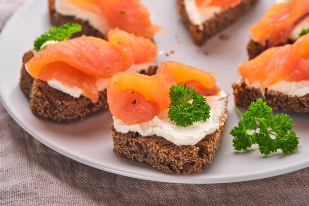 Mini bocadillos de salmón, requesón, perejil y pan de centeno en forma de corazones. Comida creativa casera de San Valentín. Amo el diseño del desayuno. Enfoque selectivo y espacio de copia.