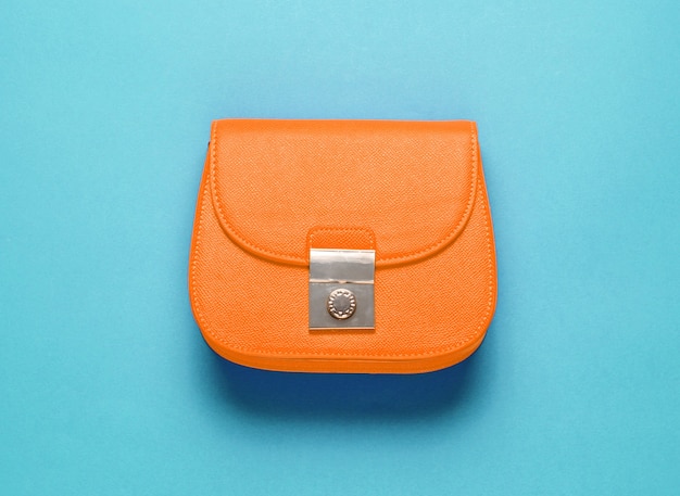 Mini bolso de piel naranja sobre fondo morado. Concepto de moda minimalista. Vista superior