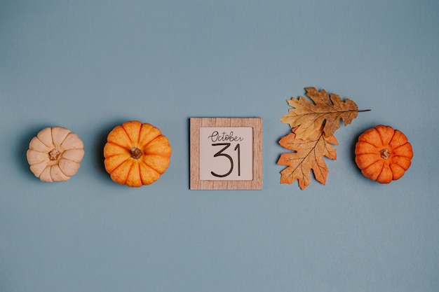 Mini calabazas naranjas y fecha calendario en marco de madera