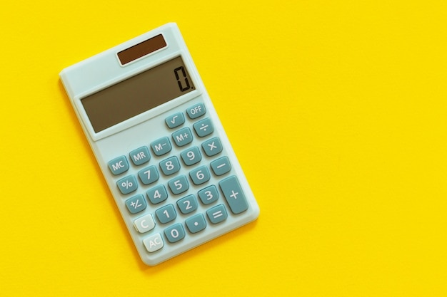 Mini calculadora em fundo amarelo. Vista superior, configuração plana.