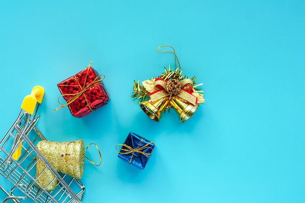 Mini carrinho de compras com enfeites de Natal em fundo azul para o dia de Natal e feriados c