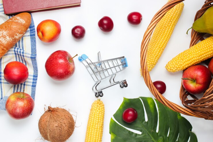 Foto mini carrinho de compras com frutas e cesta em um fundo branco. folha de monstera.