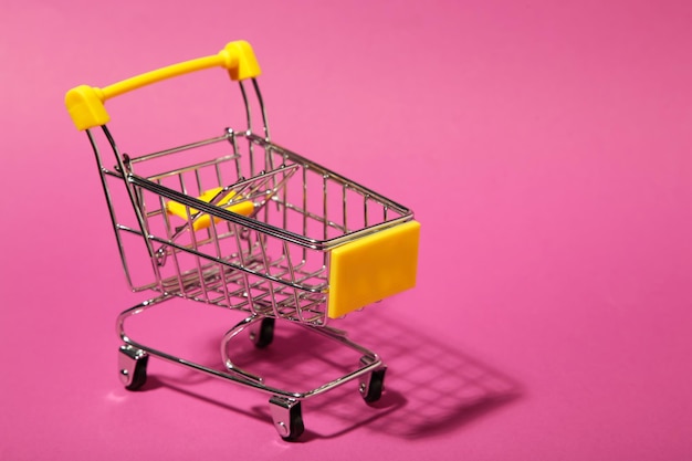 Foto mini carrinho de compras em fundo rosa
