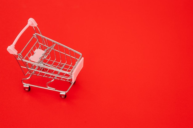 Mini carrinho de compras em fundo vermelho