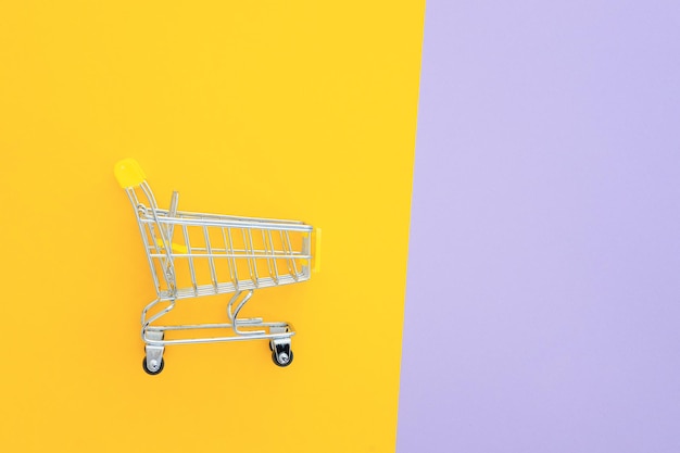 Mini carrinho de supermercado em fundo amarelo violeta
