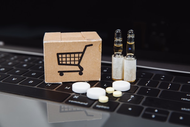 Mini carrito de compras lleno de remedios homeopáticos en el fondo de la computadora portátil. Concepto de compras online homeopatía e internet.
