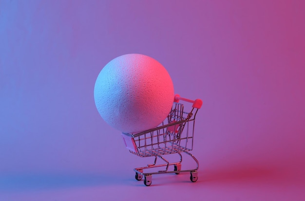 Mini carrito de compras con una pelota en luz de neón azul rojo Arte conceptual surrealista