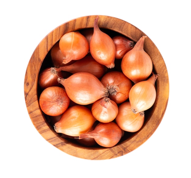 Mini cebollas marrones en un tazón de madera aislado en un fondo blanco Bulbos de cebolla crudos para el cultivo Cebolla francesa Vista superior