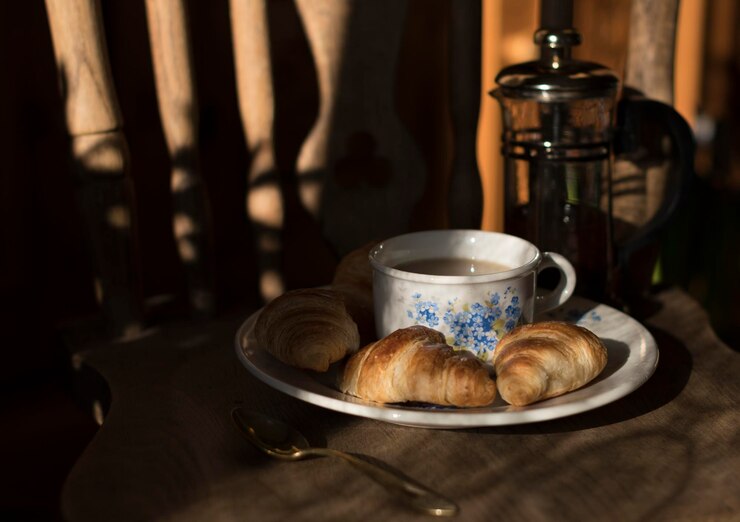 Foto mini croissants frescos para o pequeno-almoço da manhã em um prato com uma chávena de café