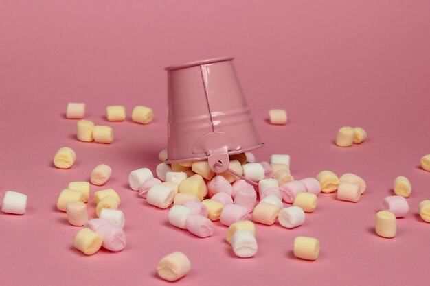 Mini cubo con muchos malvaviscos sobre un fondo rosa pastel. Minimalismo. Dulces