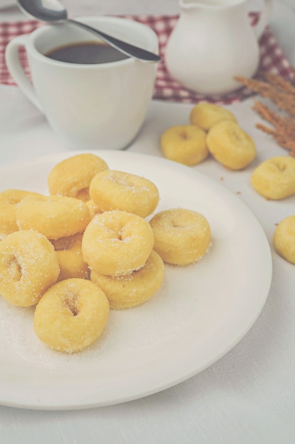 mini donuts na chapa branca e uma xícara de café.