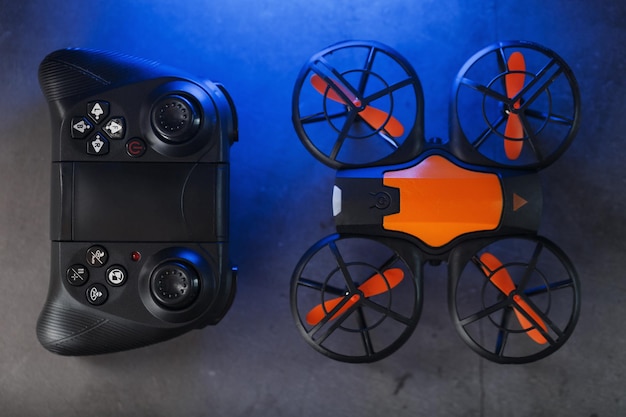 Mini drone laranja para jogos em um fundo escuro com um controle de joystick