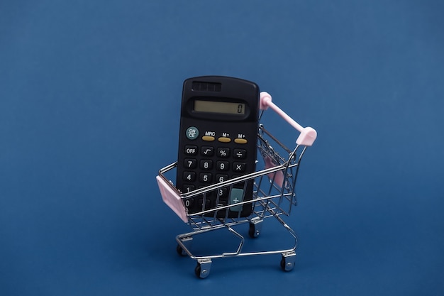Mini-Einkaufswagen mit Taschenrechner auf klassischem blauem Hintergrund