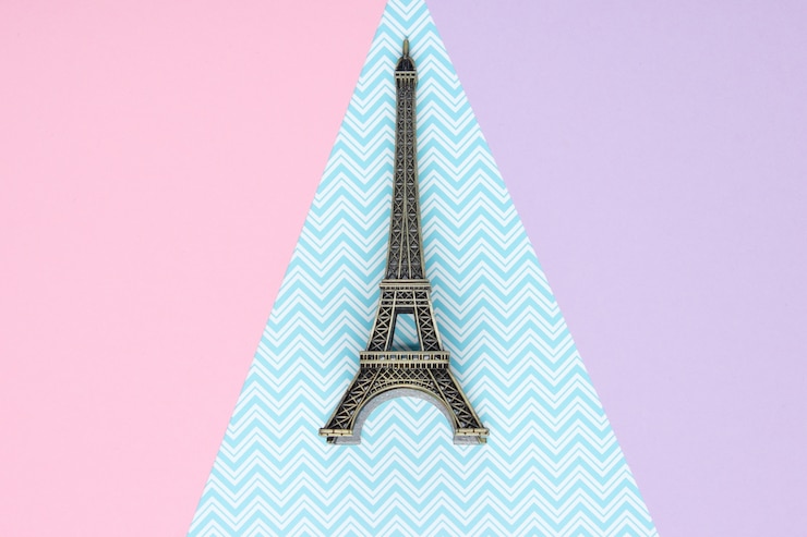 Foto mini estatuilla de la torre eiffel sobre una mesa de papel pastel. vista superior