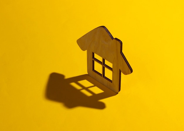 Mini figura de casa em um fundo amarelo. Foto de estúdio com sombra