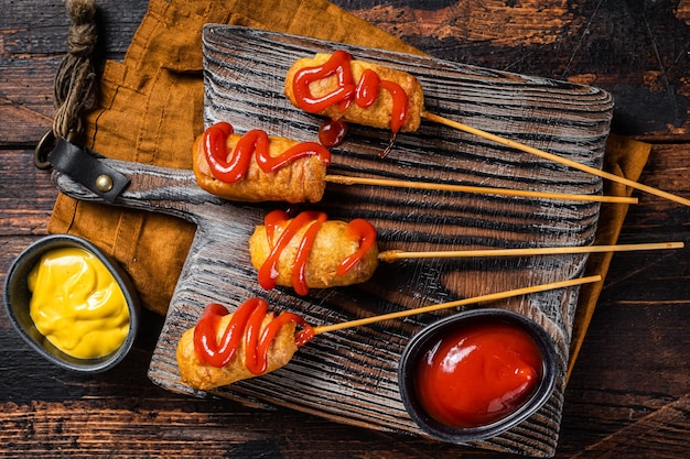 Mini frittierte Maishunde mit Senf und Ketchup auf Holzbrett Holzhintergrund Ansicht von oben