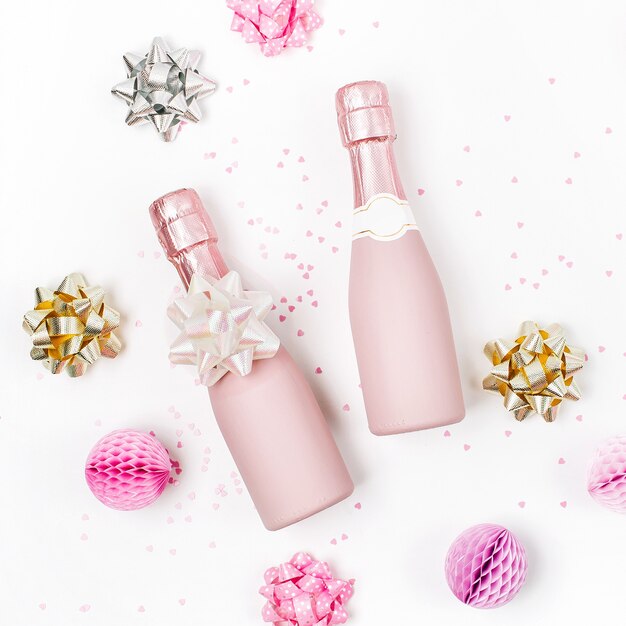 Mini garrafas de champanhe rosa pálido com confete e enfeites. Postura plana. Tema de conceito de celebração de ano novo / Natal ou casamento. Camada plana, vista superior