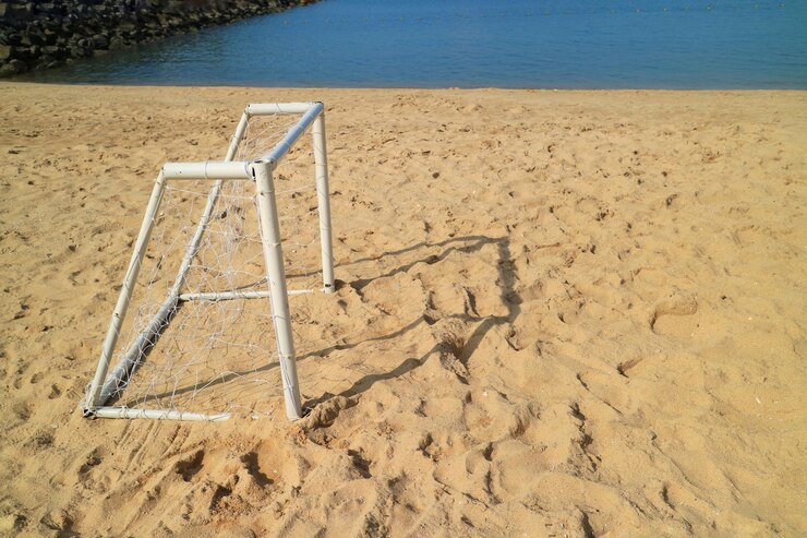 Foto mini gol de futebol na praia com mar azul e areia no verão