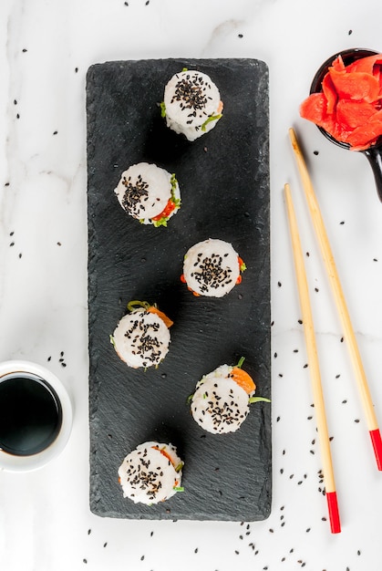 Foto mini hamburguesas de sushi, sándwiches con salmón, hayashi wakame, daikon, jengibre, caviar rojo.