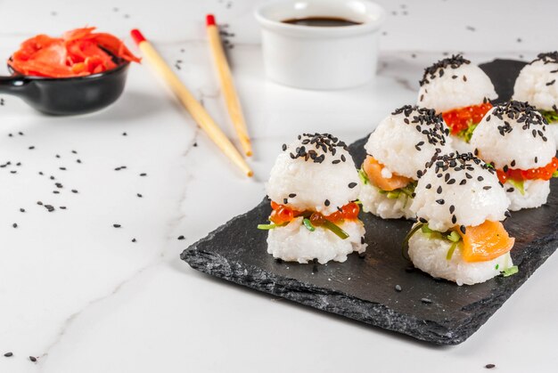 Foto mini hamburguesas de sushi, sándwiches con salmón, hayashi wakame, daikon, jengibre, caviar rojo.