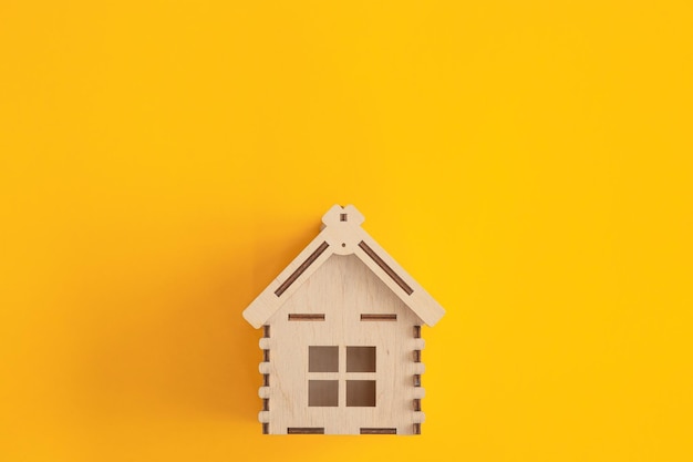 Mini-Holzhaus auf gelbem Hintergrund Wohn- und Hausdarlehenskonzept