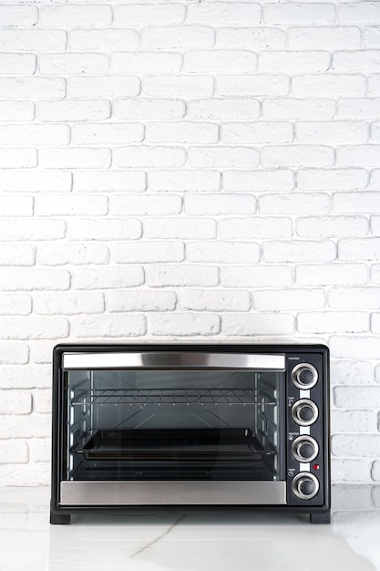 Mini horno eléctrico contra la pared de ladrillo blanco en la cocina