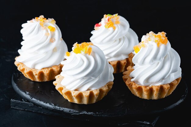 Mini-Kuchenkorb mit Baisercreme auf schwarzem Hintergrund