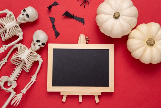 Mini leere Kreidetafel mit Kopierbereich und Halloween-Dekor auf rotem Hintergrund Süßes oder Saures Flaches Lay