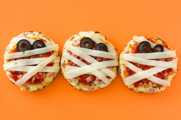 Mini momias de Halloween mini pizzas sobre fondo naranja