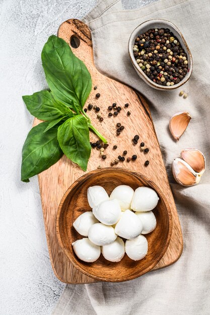 Mini-Mozzarella-Käse in einer Holzschale mit Basilikumblättern