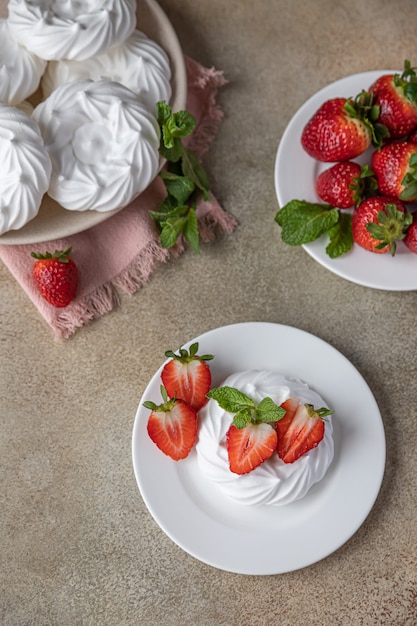 Mini nido de merengue con fresas y menta en un plato, nido de merengue vacío y fresas