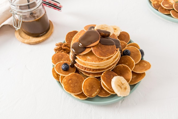 Mini panquecas caseiras frescas em uma placa de cerâmica com pasta de chocolate stackaya sobre eles delicioso café da manhã para flocos alternativos de crianças