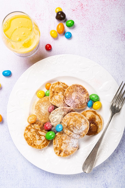 Mini panquecas holandesas chamadas poffertjes com colorido açúcar de confeiteiro e doces. Conceito de comida saudável, visão plana, vista superior