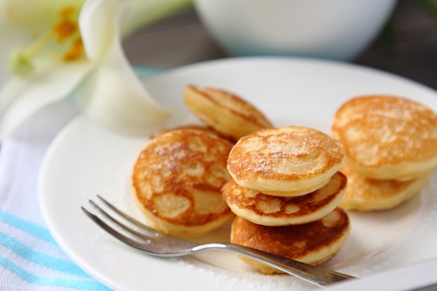 Mini panquecas holandesas chamadas poffertjes, polvilhadas com açúcar de confeiteiro