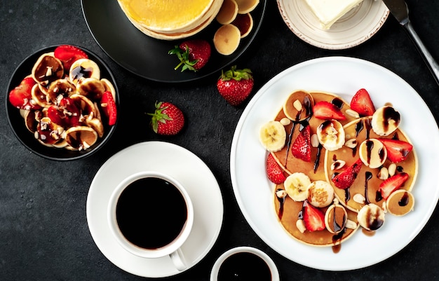 Mini panqueques con fresas y plátanos en platos sobre la mesa